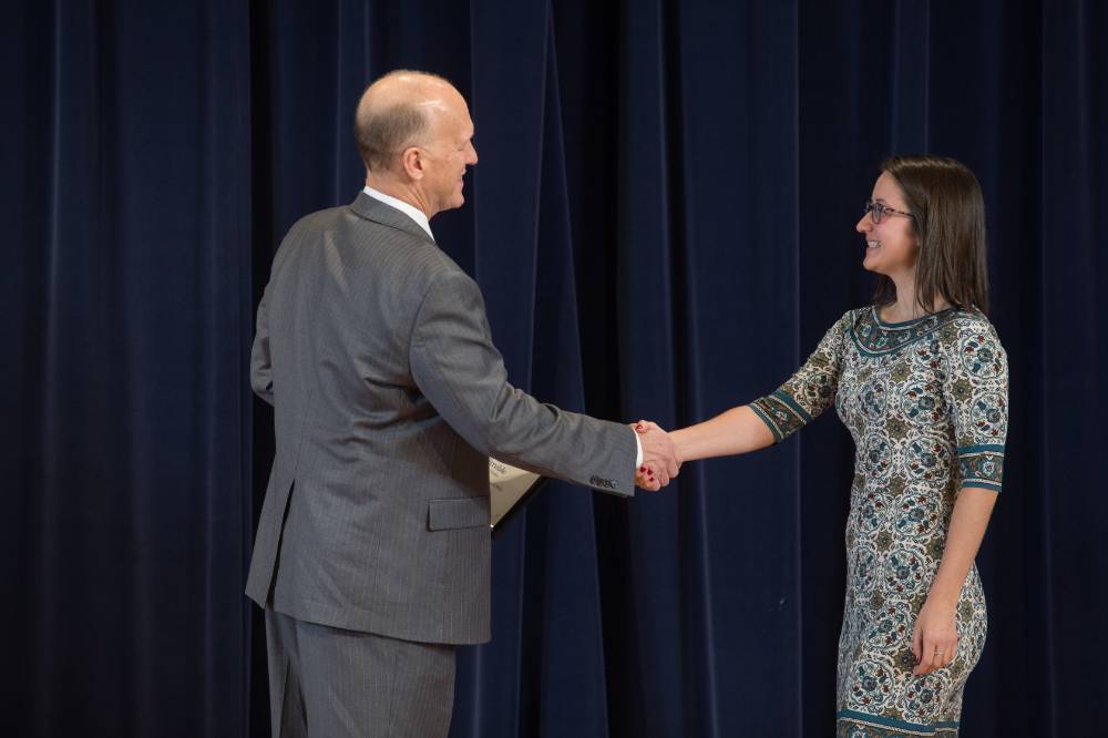 Woman smiling and shaking hands with Dean Potteiger as she receives her award